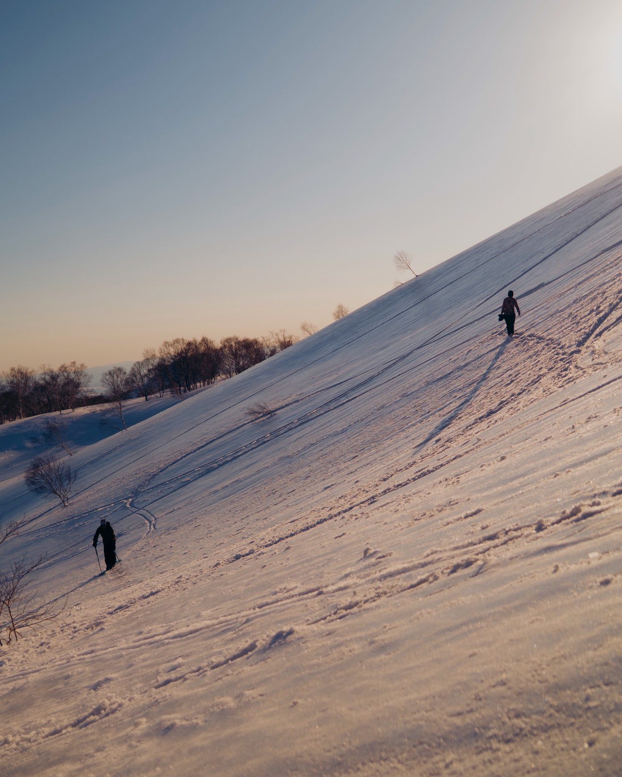 夕暮れの雪面を登る二人